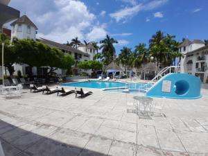 a swimming pool with chairs and a blue slide at Beachview 1 bedroom 15 in Ocho Rios