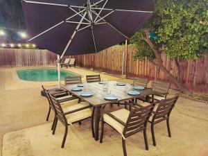 a wooden table with chairs and an umbrella next to a pool at Old Fig House - Historic Fig Garden Neighborhood in Fresno