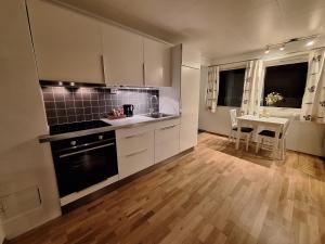 a kitchen with white cabinets and a table with a dining room at Central and comfortable apartment in Tromsø in Tromsø