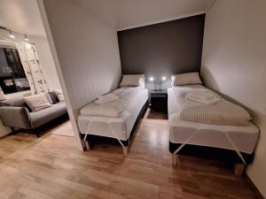 two beds in a small room with a couch at Central and comfortable apartment in Tromsø in Tromsø