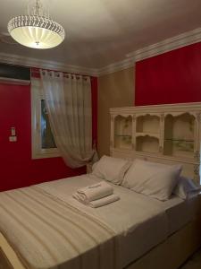 a bedroom with a white bed with a red wall at B&KHOME Banha in Banī Ghālib