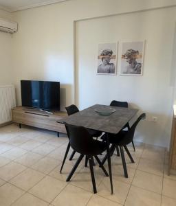 a dining room with a table and chairs and a tv at Domus Philippi & parking in Larisa
