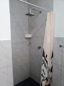 a shower with a glass door with a shower curtain at modern loft facing the sea in Puerto Máncora