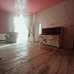 Una sala de estar con piano y suelo de madera. en Retro House, en Częstochowa