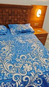 a bed with a blue and white comforter on it at Oumou et Aicha in Dakar