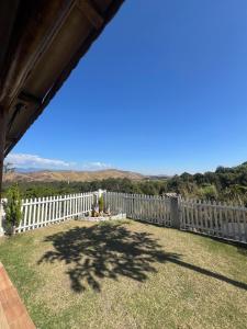a backyard with a white picket fence and a tree at Chácara vó Zenilda in Itatiaia