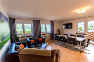 ein Wohnzimmer mit Sofas, einem Tisch und Stühlen in der Unterkunft Ski-n-Lake City Apartments in Zell am See