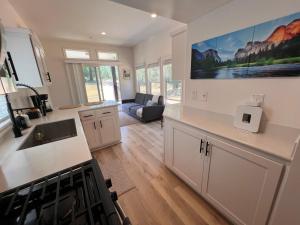 a kitchen with white cabinets and a living room at Tiny House Village Yosemite-Blanca in Groveland +19 photos