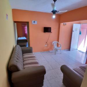 a living room with a couch and a tv at Refúgio da Paz - Itanhaém in Itanhaém