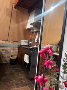 a kitchen with a stove and some pink flowers at Cabaña del Campo in Santa Rosa de Copán