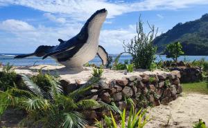 a large whale statue sitting next to a rock wall at Rurutu Randy