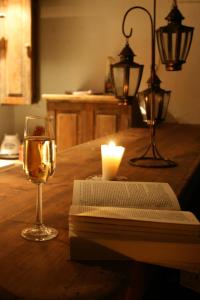 a candle and a glass of wine and a book on a table at Cabañas Biuzaa in Zipolite