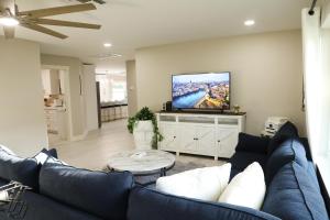 ein Wohnzimmer mit einem blauen Sofa und einem Flachbild-TV in der Unterkunft Brand NEW Renovated Coastal Beach House in Naples