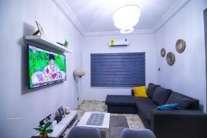 Una sala de estar con un sofá y un televisor de pantalla plana. en East Legon Luxury Stay - AC, Wifi, Netflix, en Accra
