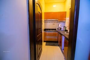 una cocina con armarios de madera y un pasillo con microondas en East Legon Luxury Stay - AC, Wifi, Netflix, en Accra 13 fotos más