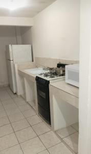 Una cocina con estufa y refrigerador blanco. en Casa Victoria, en Gómez Palacio