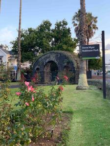 a sign in a park with flowers and a palm tree at Auckland City Holiday Escape in Auckland +3 photos