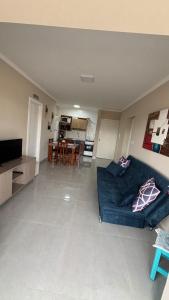 a living room with a blue couch and a kitchen at Aconchegante apartamento com piscina in Capão da Canoa +9 photos