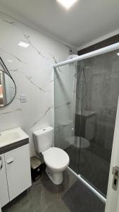 a bathroom with a toilet and a glass shower at Aconchegante apartamento com piscina in Capão da Canoa