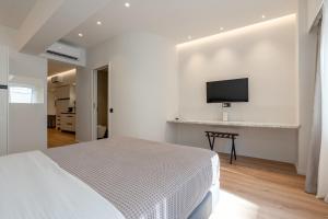 a white bedroom with a bed and a tv on a wall at ERMOU 40 SUITES in Athens
