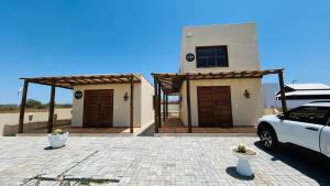 a house with a car parked in front of it at Mar e Terra Bangalôs in Areia Branca