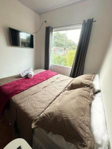 a bedroom with a bed and a window at Pousada Sol e Mar Dias Cezar in Paraty