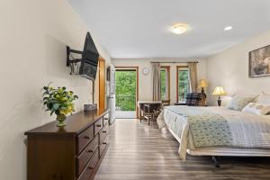 a bedroom with a bed and a dresser with a television at Ackerview Guesthouse Bed and Breakfast in Salmon Arm