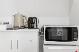 a microwave oven sitting on top of a white cabinet at Blenheim Accommodation in Blenheim +32 photos