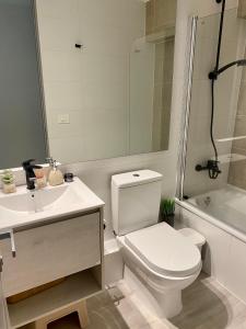 a bathroom with a toilet and a sink and a tub at Acogedor departamento de lujo in Pucón