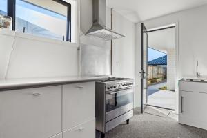 a kitchen with white cabinets and a stainless steel stove at Blenheim Accommodation in Blenheim +34 photos