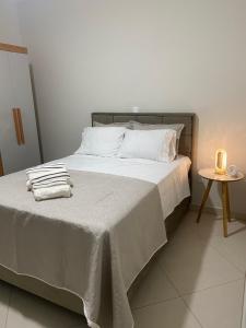 a bed with white sheets and a candle on it at Lar Urbano in Manhuaçu