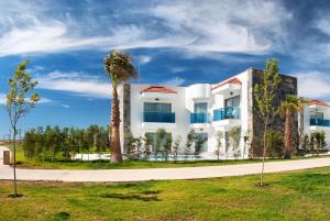 a white building with a palm tree in front of it at Aquasis De Luxe Resort & SPA - Ultra All Inclusive in Didim