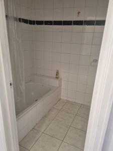 ein Badezimmer mit Badewanne und Fliesenboden in der Unterkunft Little Yellow Guesthouse in Melbourne