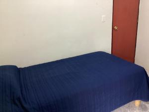 a bed with a blue blanket on top of it at Habitación privada zona Satélite in Mexico City