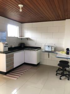a kitchen with white appliances and a table and a chair at Recanto Urbano Centro histórico in São José