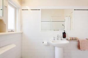 パースにあるFloreat Family Home - With Kids Play Equipmentの洗面台と鏡のある白いバスルーム +46枚の写真