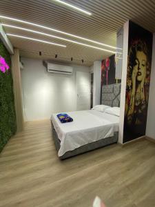 カリにあるApartahotel brisas de los alamosの壁に絵が飾られた大きなベッドのある寝室