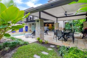 a patio with a table and chairs under an umbrella at SeaEden Port Douglas Apartments in Craiglie