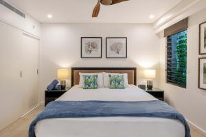 a bedroom with a large bed and two lamps at SeaEden Port Douglas Apartments in Craiglie +22 photos