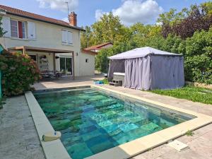 a swimming pool in front of a house with a tent at VILLA BELLA avec piscine et jacuzzi in Saint-Fons