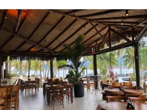 un restaurante con mesas y sillas de madera y un gran techo en FLAT ILHA FLAT HOTEL, en Ilhabela