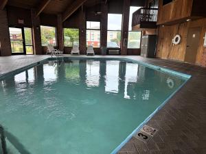 a large swimming pool with green water in a building at Baymont by Wyndham Tupelo in Tupelo