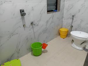 a bathroom with a toilet and buckets on the floor at Green View Homestay in Siliguri