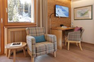 a living room with a chair and a desk at Hotel Burgwald - Ski In & Ski Out in Lech am Arlberg