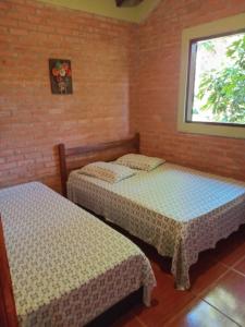 ein Schlafzimmer mit zwei Betten und einem Fenster in der Unterkunft Chalés e Camping 4 Estações in São Thomé das Letras