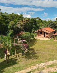 ein Haus auf einem Feld mit einem Garten mit Bäumen in der Unterkunft Chalés e Camping 4 Estações in São Thomé das Letras