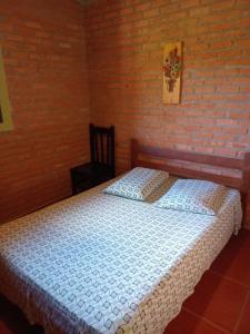 ein Schlafzimmer mit einem Bett und einer Ziegelwand in der Unterkunft Chalés e Camping 4 Estações in São Thomé das Letras