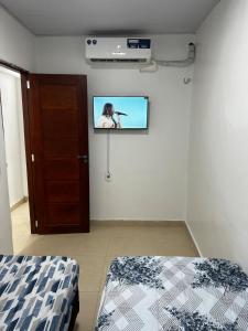 a room with a tv on a wall with a bed at Suspenso aluguel in Belém
