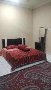 a bedroom with a bed with a red blanket and a rug at Riverview Homestay Sekoh Kuala Krau in Kuala Kerau