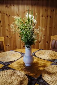 a vase filled with flowers sitting on a table at Namelis prie Magnolijos in Druskininkai
